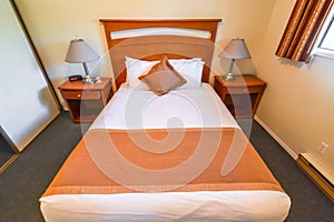 Interior of hotel bedroom with double bed and lamps on bedside tables.