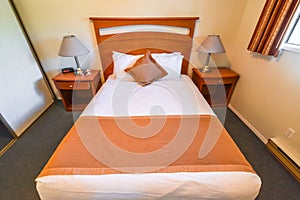 Interior of hotel bedroom with double bed and lamps on bedside tables.