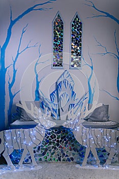 The interior of the ice castle. Two stained glass windows in the medieval style. Blue trees on the wall. Throne sofa