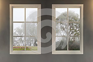 Interior image of English home style show two windows in warm living room see through the landscape natural view of big trees