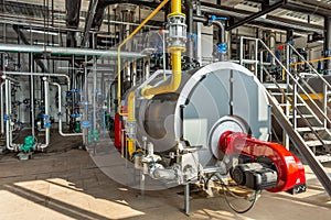 Interior of an industrial boiler room with boilers, many pipes, valves and sensors