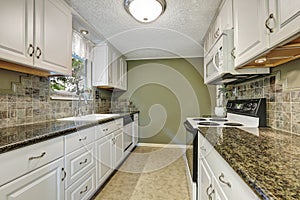 Interior of kitchen room with white cabinets, granite tops