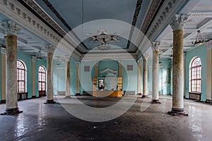 Interior of large column hall with fretwork at abandoned mansion