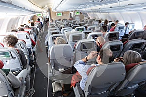 Interior of large commercial airplane with passengers on their seats during flight.