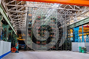 The interior of a large warehouse of heavy iron products and metal goods with pallet storage shelves at a production forge plant