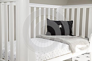 Interior of a light baby room with a soft pillow and blanket on a modern whitewashed cozy crib