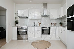 Interior of light kitchen with washing machine, oven and white counters