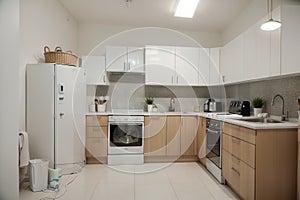 Interior of light kitchen with washing machine, oven and white counters
