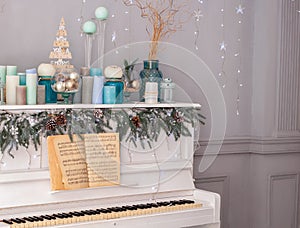 Interior living room is decorated in classic style with white piano, Christmas tree and gifts. New Year decoration. Piano in room