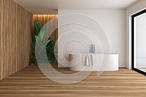 Interior of loft Scandinavian style bathroom with white and wood walls, wooden floor, white bathtub standing near window