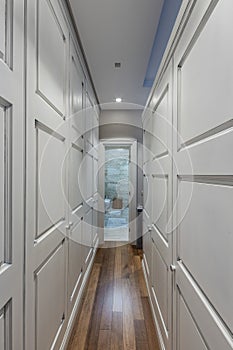 Interior of a long corridor with closet doors and brown wooden floor
