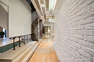 Interior of a long corridor with white brick wall