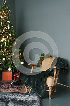Interior of a luxurious classic living room with a Christmas tree, a comfortable armchair with a blanket and gifts