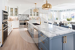 Interior of luxurious modern classic kitchen with dining area. White and blue cabinets with gilded handles, kitchen