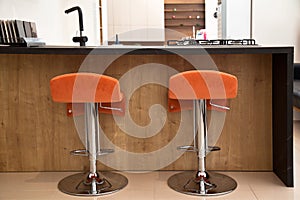 Interior of luxurious wooden modern kitchen and orange chair