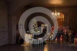 Interior of luxury dark living room with fireplace, comfortable sofa and chandelier decorated with Christmas tree and