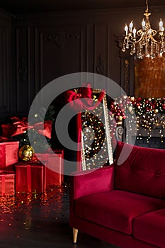 Interior of luxury dark living room with fireplace, comfortable sofa and chandelier decorated with Christmas tree and