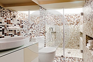 Interior of a modern bathroom with brown tiles with a large shower cabin