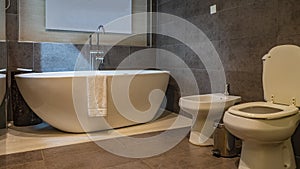 The interior of a modern bathroom. A white towel draped over the edge of a large oval acrylic bathtub.