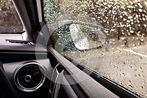 Interior of a modern car with an air conditioning vent and mirror in a rainy weather