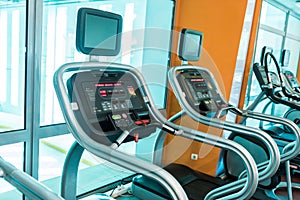 Interior of modern gym fitness room with large windows and treadmills