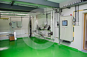 The interior of a modern industrial gas boiler room. Pipelines, water pumps, valves, manometers.