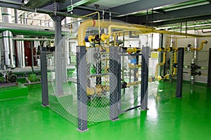 The interior of a modern industrial gas boiler room. Pipelines, water pumps, valves, manometers.