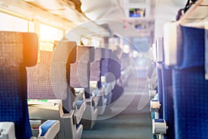 Interior of modern intercity express train. Back view of wide comfortable seats in row at railroad transport. Sunrise light thro