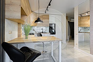 Interior of a modern kitchen, with a bar with wooden inserts and white marble tiles, in a small apartment