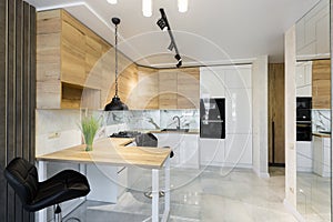 Interior of a modern kitchen, with a bar with wooden inserts and white marble tiles, in a small apartment