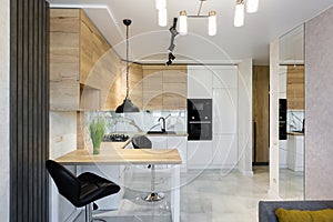 Interior of a modern kitchen, with a bar with wooden inserts and white marble tiles, in a small apartment