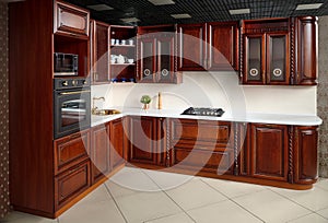 Interior of modern kitchen in classic style with golden elements cherry alder wood cabinetry with built-in appliances electric or