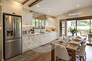 Interior of modern comfortable kitchen with fridge, counter, and dining table