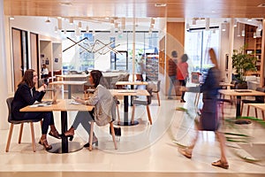 Interior Of Modern Open Plan Office With People Working And Commuters Arriving On Bikes