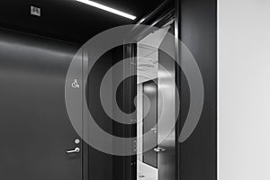 Interior of a modern public restroom with grey clay tiles and anthracite doors.