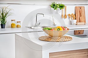 Interior of modern white kitchen with induction cooking heater an vegetables on the table