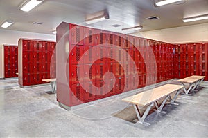 A high school locker room with metal lockers, and wood benches. photo