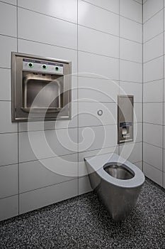 Interior of new and modern clean public restroom with white tiles and stainless steel bowl