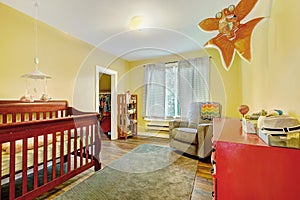 Interior of nursery room with crib, red chest of drawers