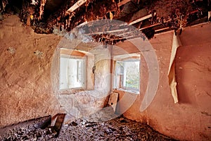 Interior of an old abandoned cottage with peeled walls and windows