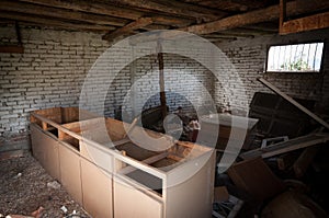 Interior of an old abandoned house kitchen with damaged furniture and a messy floor