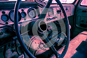 Interior of old abandoned truck, grunge background with rusty dashboard and driving wheel