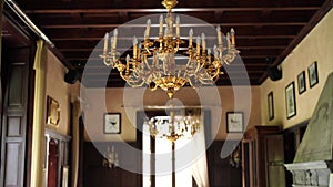 The interior of an old Italian villa, large windows and a large golden chandelier with candles.