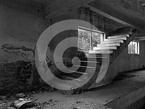 Interior of an old messy abandoned concrete building. Stairs to the upper floor in empty industrial warehouse
