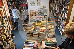 Interior of old secondhand book shop store with stacks of books and customers