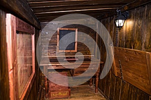 Interior of old ship cabin with wooden panels and cords.