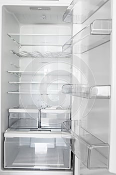 Interior of an open empty branch new refrigerator with shelves compartments for ergonomic food storage. Home kitchen appliances