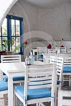 Interior of outdoor greek restaurant with white and blue chairs.