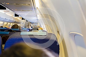 Interior of passenger airplane with people on seats