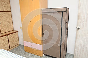 An interior photo of a bedroom with stand alone and flushed wall wooden wardrobe cardboard cabinets